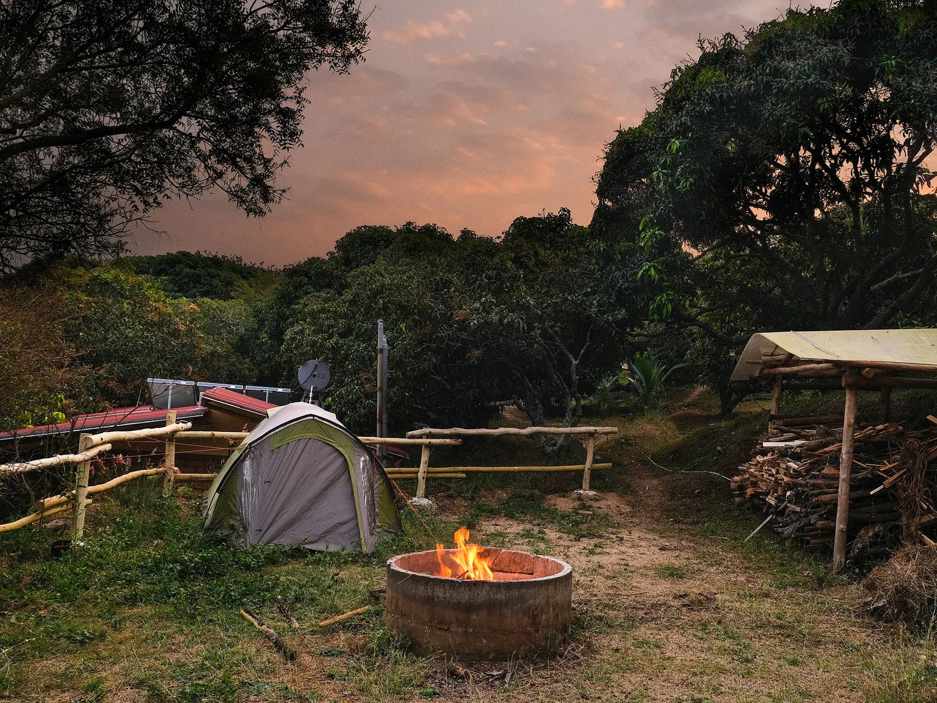 Tents around a glowing campfire at dusk at Similitude.