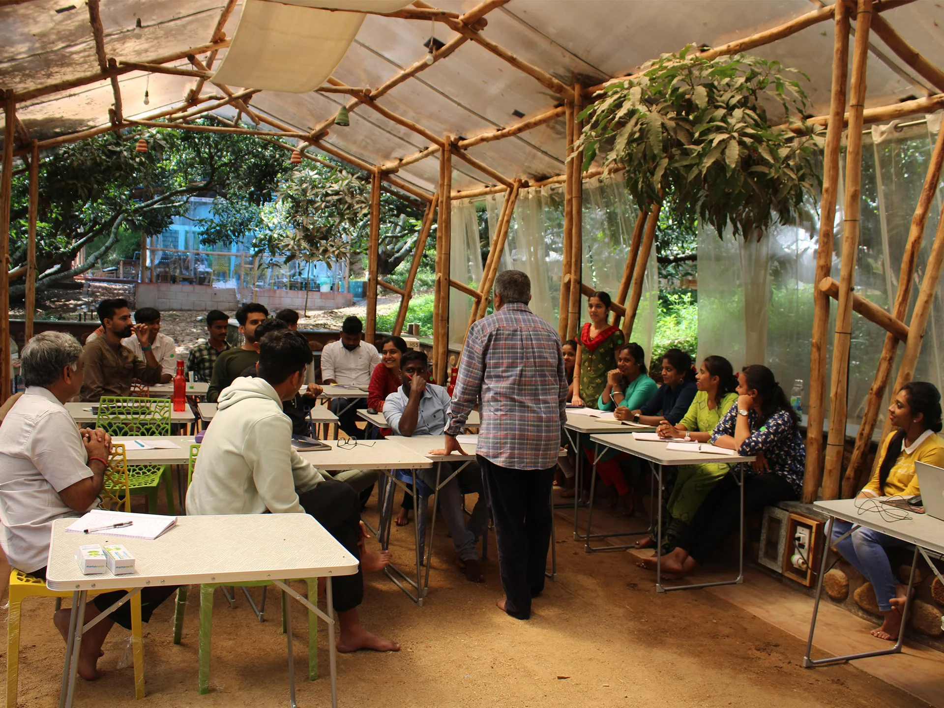 Participants working together at tables in an open-sided shelter.